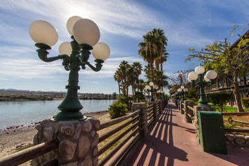Riverwalk In Laughlin Nevada. Streetlights and palm trees line the empty  riverwalk along the Colorado River in the downtown Laughlin Nevada casino district. 
