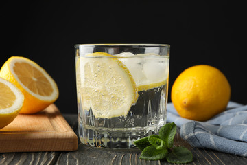 Glass with lemonade and ingredients on wooden background, close up
