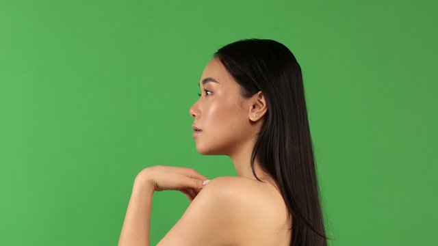 Close up shot of an angry young asian woman isolated on green background