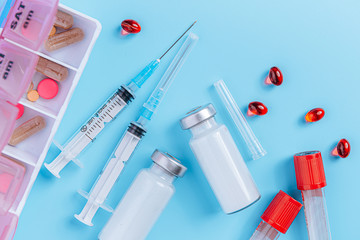 two syringes and two ampoules with medicine without a label on a blue background the concept of a coronavirus vaccine
