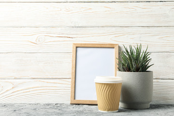 Succulent, coffee and frame on white wooden background, space for text