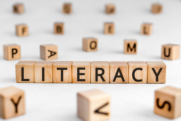 Literacy - word from wooden blocks with letters, literacy the ability to read and write concept, random letters around white background
