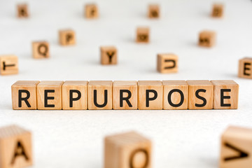Repurpose - word from wooden blocks with letters, adapt to find a new use for an idea, product, or building repurpose concept, random letters around white background