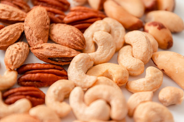 Close up assorted brown nuts on a gray background. Macadamia, cashews, minced almonds, pecans, wholesome food