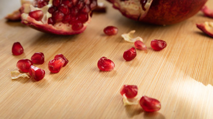 grains of red ripe pomegranate on a wooden board on a table