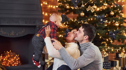 Obraz premium Beautiful caucasian couple celebrating christmas indoors with their little son