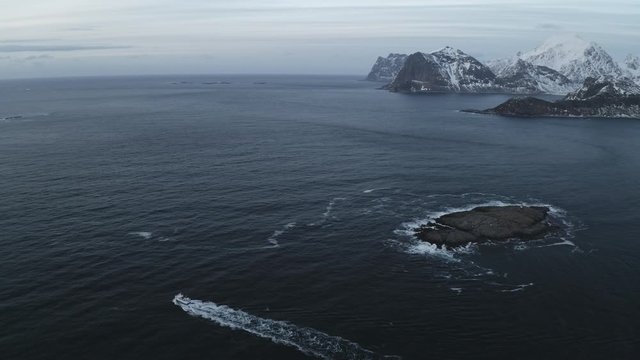 Fishing boat sailing to the ocean in arctic area of Lofoten Islands located north of norway during winter.Winter is main fishing season and cod fish is very famous from Norway.Mountains in background