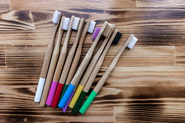 many multi-colored bamboo toothbrushes lie on a wooden background. eco friendly. texture