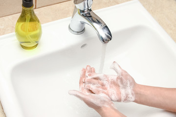 A Washing hands with soap under the faucet with water
