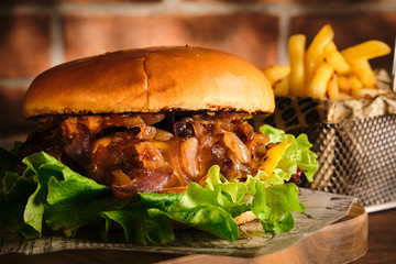 Burger with beef and caramelized onions on a wooden board. Cheeseburger with onion and beef. Juicy Delicious Homemade Burger.