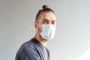 Young Blond Hair Caucasian Male Using Disposable Face Mask for Covid-19, Cought, Flu, Virus, Viral Protection Looking at the Camera