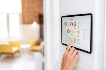 Controlling home with a digital touch screen panel installed on the wall in the living room....