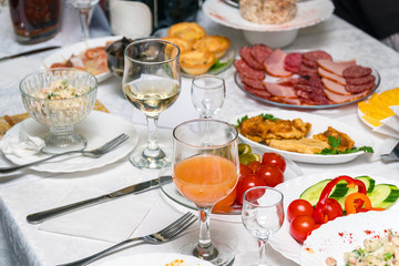 Festive table setting with crystal glasses and plates. Snacks and sandwiches on the table. Selective focus
