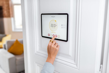 Controlling temperature in the living room with a digital touch screen panel. Concept of heating...