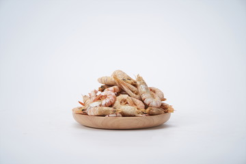 Dried shrimps on a wooden plate against a white background
