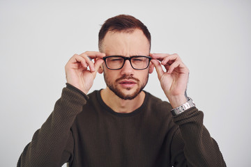 Young guy in sunglasses standing indoors against white background