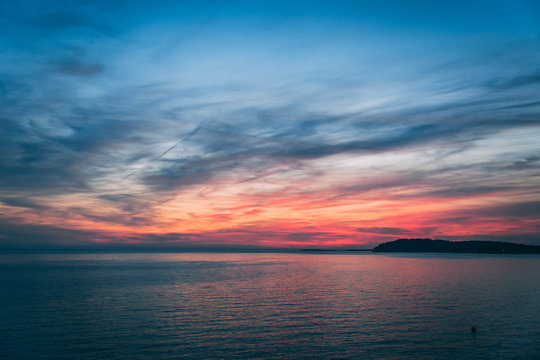 Sunset over the sea, colorful clouds, wide shot. Romantic picture full of colors.