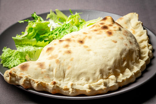 baked calzone. closed type of pizza that is folded in half. Delicious homemade food