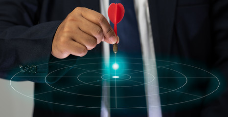 The hand of a male businessman holding a dart and aimed at the graphic target, Targeting the...