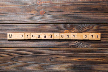 Microaggressions word written on wood block. Microaggressions text on wooden table for your desing,...
