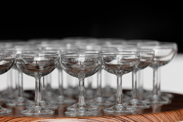 Many elegant empty glasses of wine or champagne on the wooden table in wedding day. Set of blank empty glasses displayed in rows. Preparation for the holiday