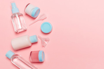 Top view composition of small travelling bottles and jars for cosmetic products on pink background. Facial skin care concept with copy space for your design