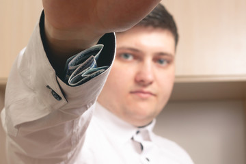 Caucasian man shows one hundred dollar bills hidden in a sleeve in a white shirt in the office