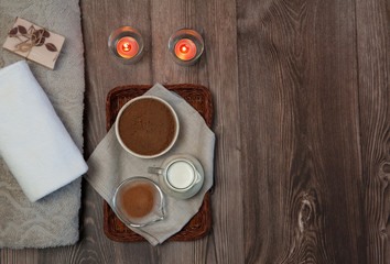 Natural home skin care. The pleasure of taking a chocolate-milk bath. Cocoa powder, cinnamon, milk, handmade soap with olive oil, burning candles and clean towels on a wooden background. Free space.