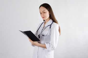 girl doctor looks in a notebook, on a light background