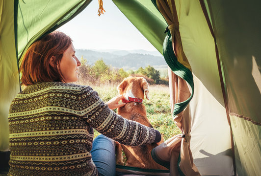 Woman with her pet beagle dog resting in camping tent.. People in outdoor concept image.