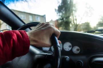 driver’s hand holds the steering wheel of the car.
