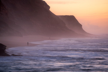 Fototapeta na wymiar Fishermen in Santa Cruz beach at sunset, in Portugal