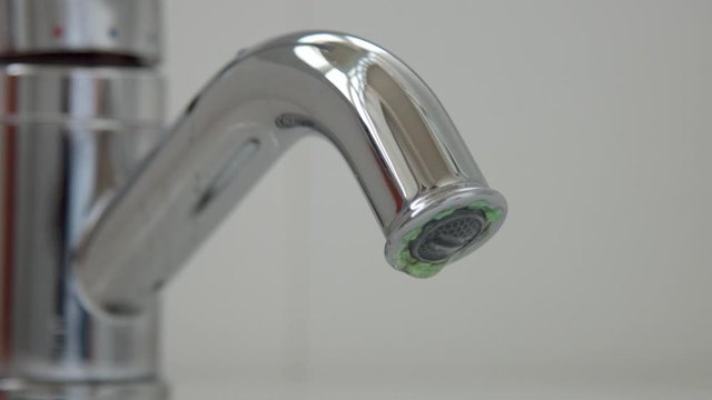 Closeup of a flowing faucet with water drops falling. Moderate consumption concept