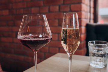 two glasses of red wine and champagne stand on a wooden table