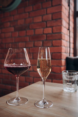 two glasses of red wine and champagne stand on a wooden table