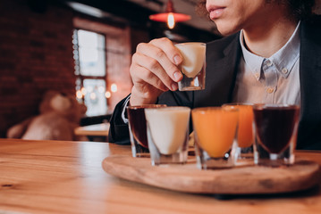 young curly-haired guy in a black suit drinking a liqueur in the bar