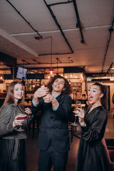 two young girls in black dresses and a curly haired guy have fun in a restaurant