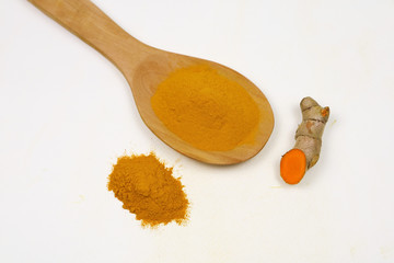 Turmeric powder in a wooden spoon and fresh turmeric root, isolated on a white background, is an ingredient in turmeric foods and ingredients in skin care products. Turmeric helps the skin to be stron