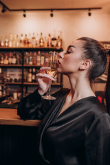 young beautiful girl in a black dress with a glass of champagne in her hands