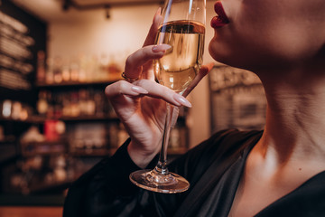 young beautiful girl in a black dress with a glass of champagne in her hands