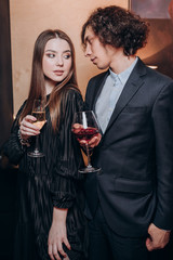 a young guy with curly hair and a beautiful girl in a dark dress together in a restaurant