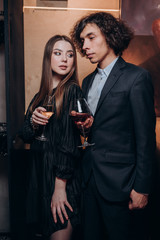 a young guy with curly hair and a beautiful girl in a dark dress together in a restaurant