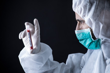 medico con tuta protettiva e mascherina tiene in mano una provetta per il test del sangue del...