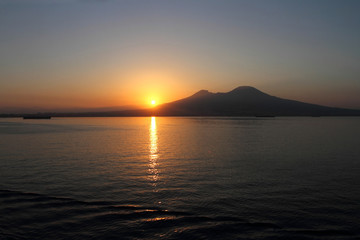 Naklejka na ściany i meble Napoli all'alba, il sole che sorge dietro il Vesuvio visto dal mare