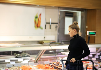 Woman shopping for fresh fish seafood in supermarket retail store	