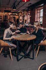 two beautiful young girls and a guy are sitting at a table in a restaurant