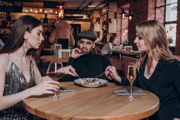 two beautiful young girls and a guy are sitting at a table in a restaurant