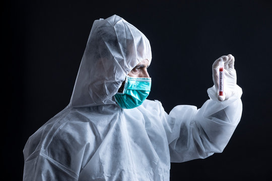 medico con tuta protettiva e mascherina tiene in mano una provetta per il test del sangue del coronavirus -   sfondo nero