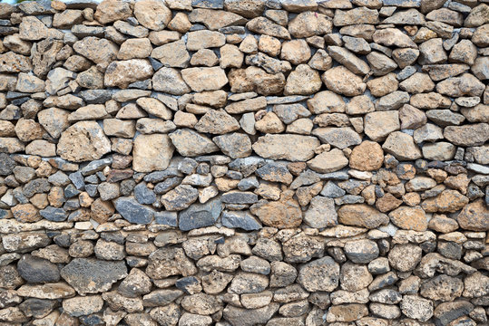 Beschaffenheit einer grauen und schwarzen Lava-Natursteinmauer als abstrakter Hintergrund