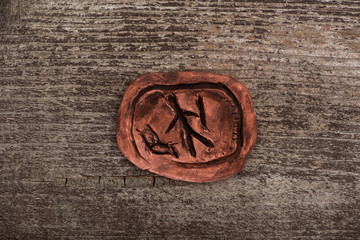 Top view of clay talisman with symbol on wooden background